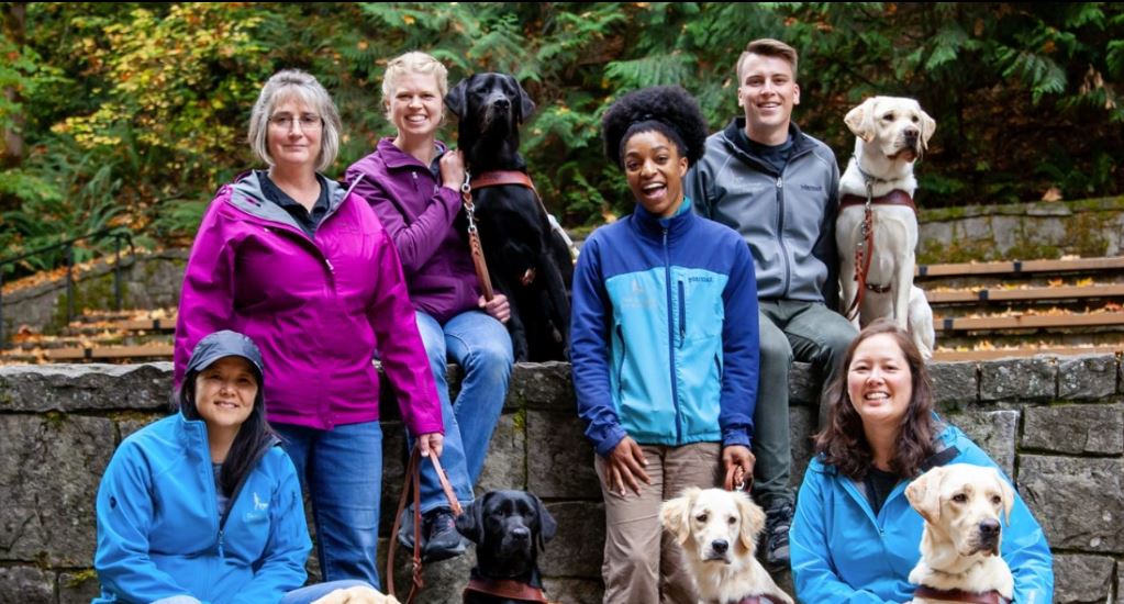 A group of GDB employees and guide dogs pose for a photo on the Oregon campus