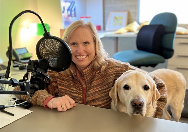 Host Theresa Stern and her guide dog Wills sit behind the mic.
