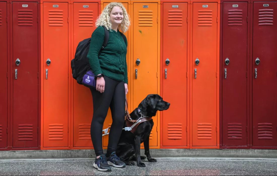 Alaina and Sable pose in front of a row of lockers in a high school hallway.